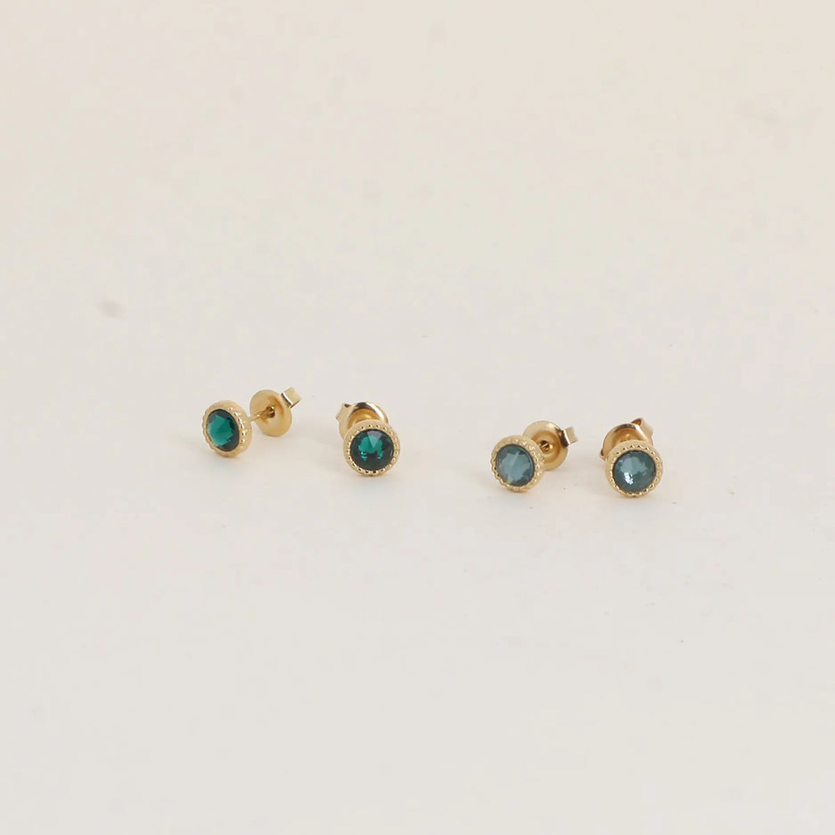 Bohm Paris Maelia kahden parin kullanvärinen kristallikorvakorusetti, jossa on kuvioitu kranssireunus ja smaragdivihreät Swarovski-kristallit.
