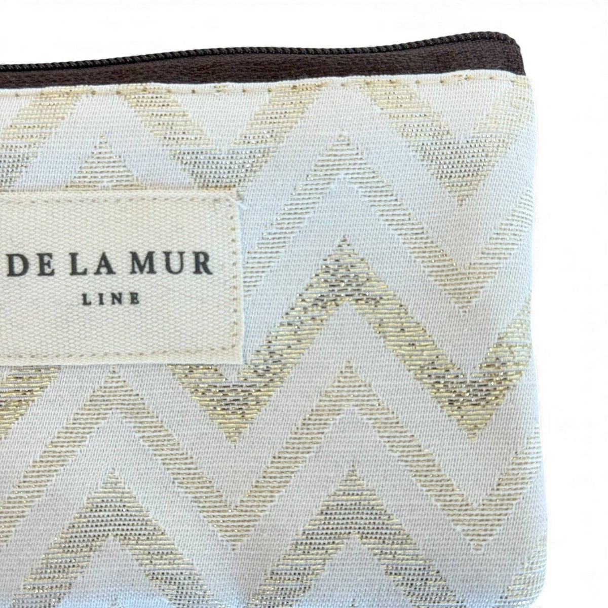 Lähikuva De La Mur Line Astro -pussukan laadukkaasta jacquard-kankaasta, jossa erottuu kimalteleva kultainen siksak-kuviointi ja vaalea logomerkki.