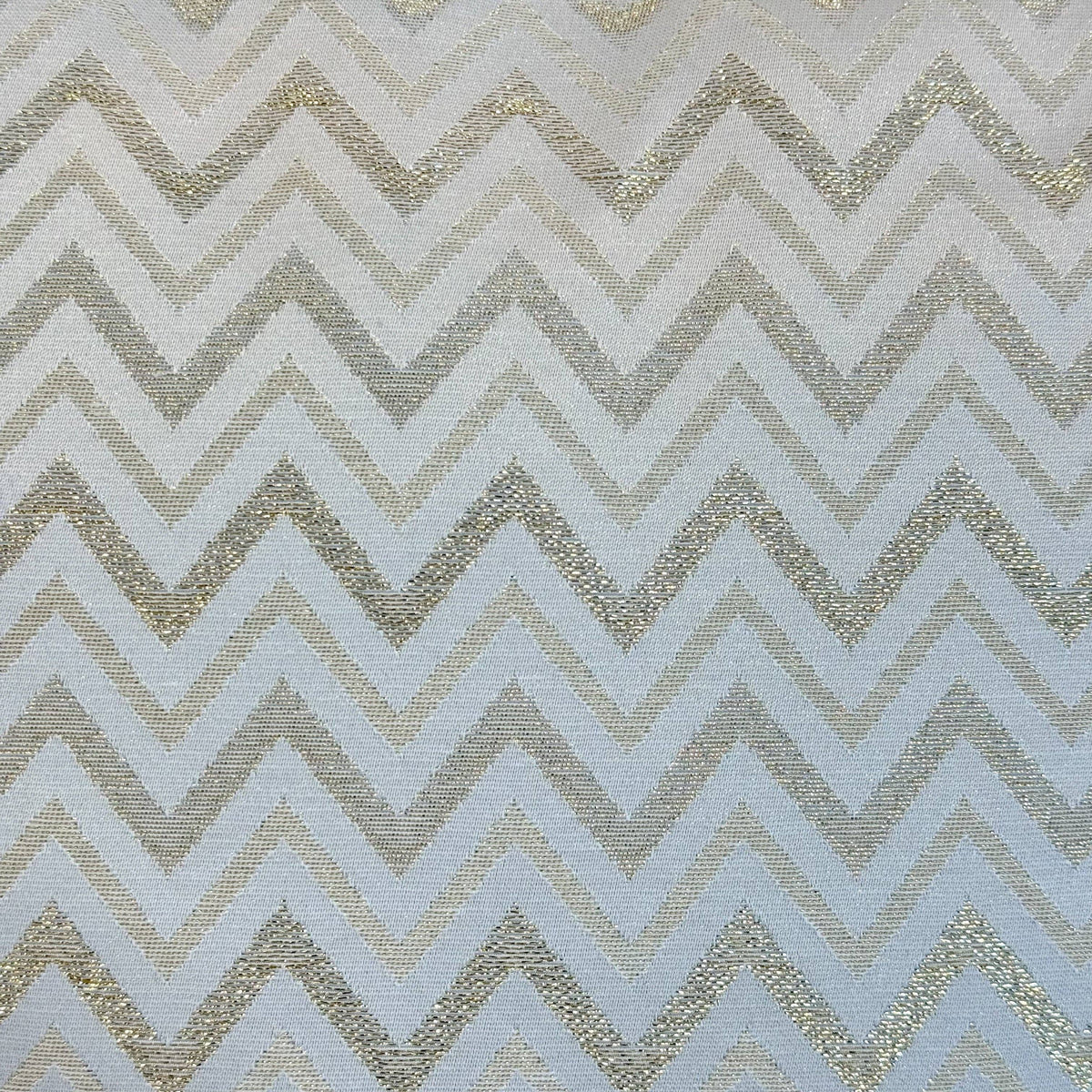 Lähikuva De La Mur Astro -sarjan valkokultaisesta siksak- ja chevron-kuvioisesta jacquard-kankaasta, jossa on kimaltelevaa lurexlankaa.