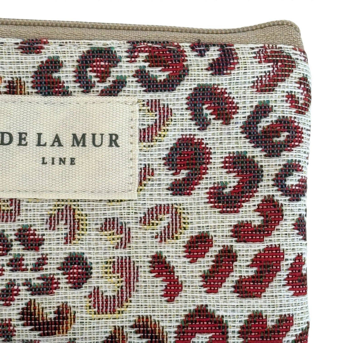 Lähikuva De La Mur Line -pussukan laadukkaasta ja jämäkästä jacquard-kankaasta, jossa erottuu punaruskea leopardikuosi ja beige brändilogo.