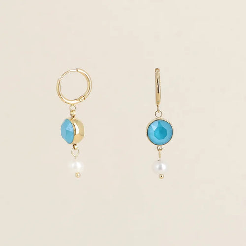 Sirot kullanväriset Bohm Paris merkkiset rengaskorvakorut, joissa roikkuu pyöreä turkoosi Swarovski-kristalli ja sen alapuolella pieni valkoinen makeanvedenhelmi.