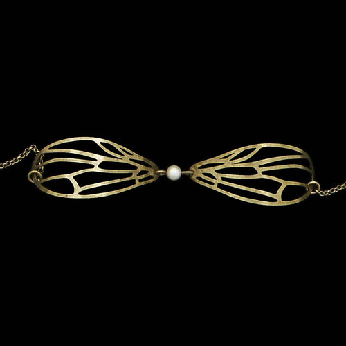 Lähikuva Amélie Blaise Dragonfly White Pearl -rannekorusta, jossa on pronssiset sudenkorennon siivet ja keskellä valkoinen helmi sirossa ketjussa.