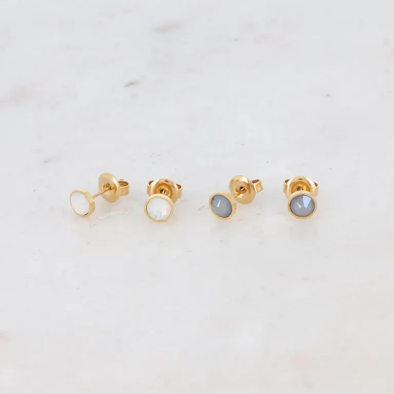 Bohm Paris Ally korvakorusetti, joka sisältää vaaleat helmiäishohtoiset ja harmaat pyöreät Swarovski kristallinapit kullanvärisellä kirurginteräsrungolla.