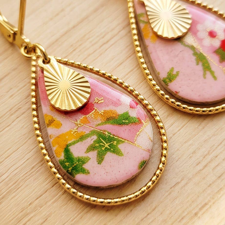 Lähikuva Elmer Jin Rose -rengaskorvakorujen pisarariipuksesta, jossa yhdistyy roosa japanilainen Washi-paperi, lehtikulta ja kultainen reunus.
